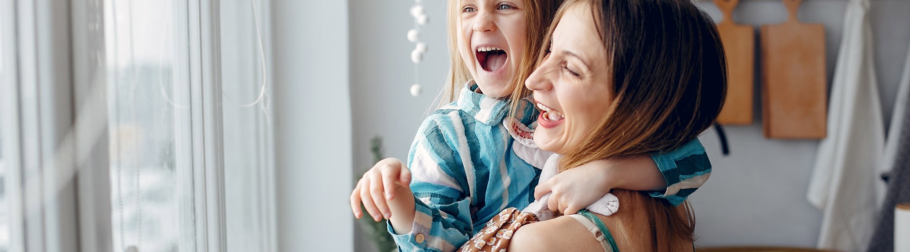 Mom and daughter laughing and looking out through a window