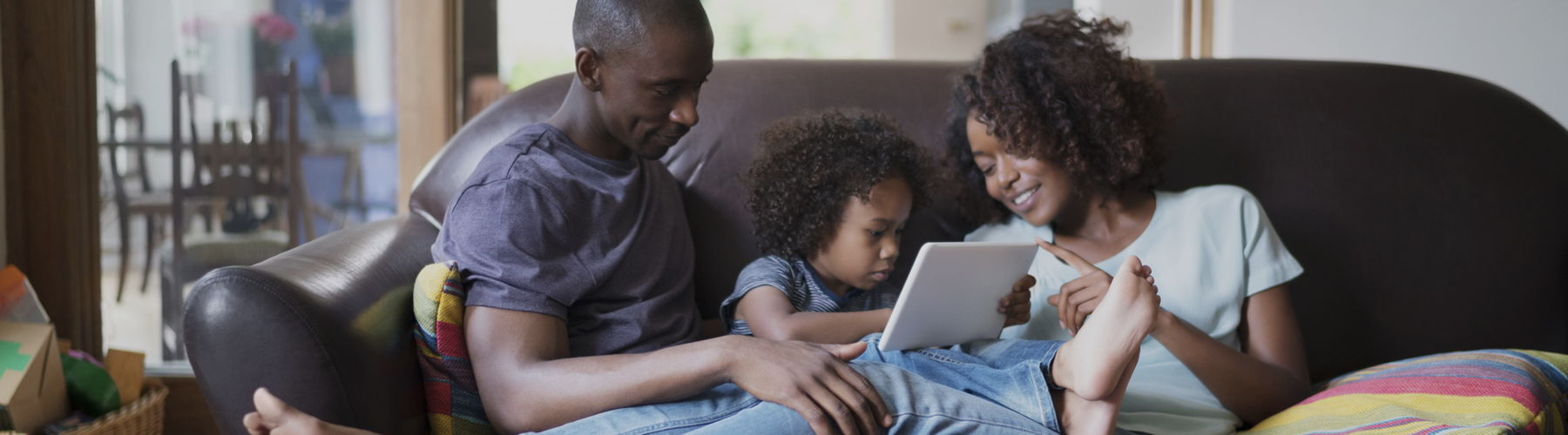 A family sitting on a couch looking at a tablet